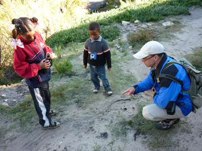 Alan shows some tracks to Caroline and Christien, the children of one of the sites domestic workers